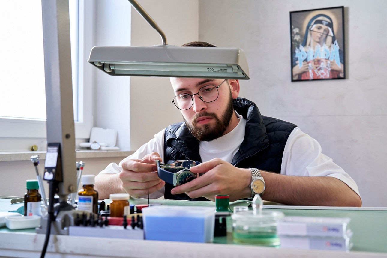 Max Müller sitzt an seinem Arbeitsplatz und arbeitet an einer Uhr