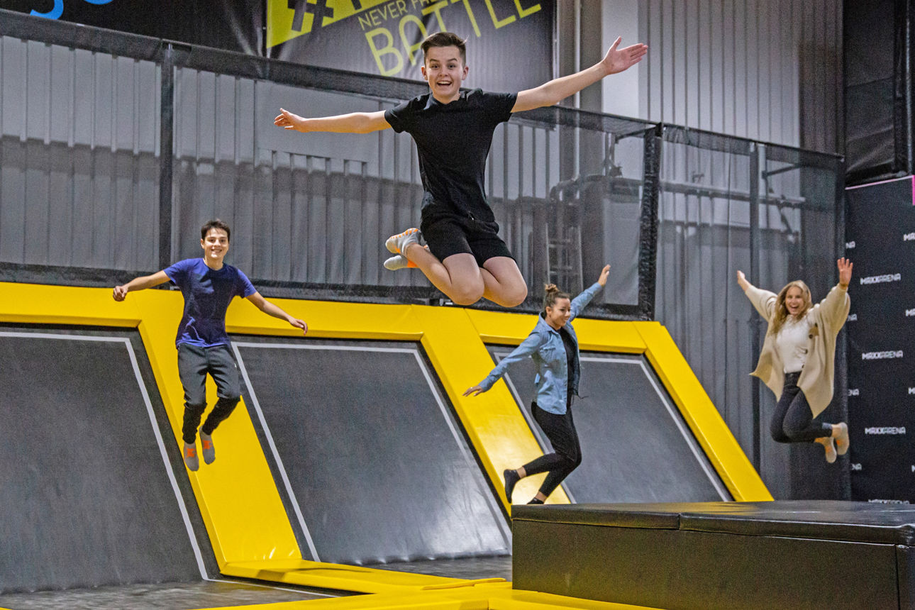 Kinder und Erwachsene springen auf einer Halle voller Trampoline