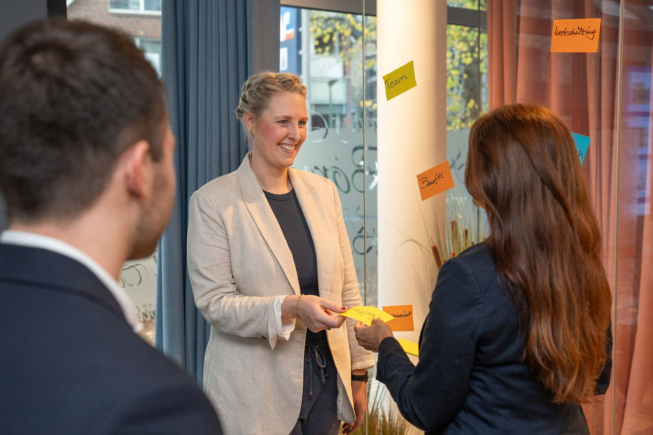 Mitarbeitende im Workshop reichen sich Notizen