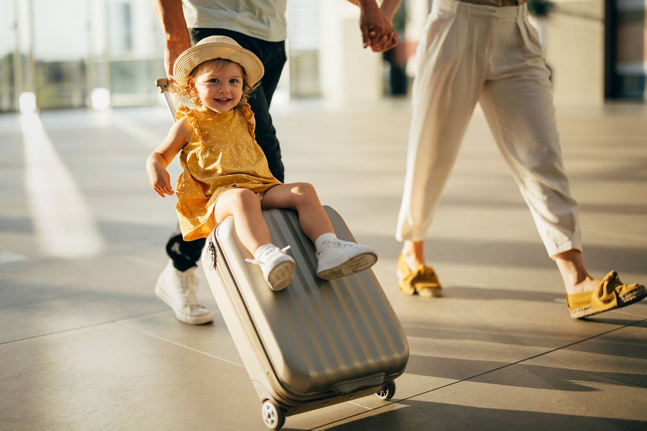 Kleines Kind sitzt auf einem Koffer.
