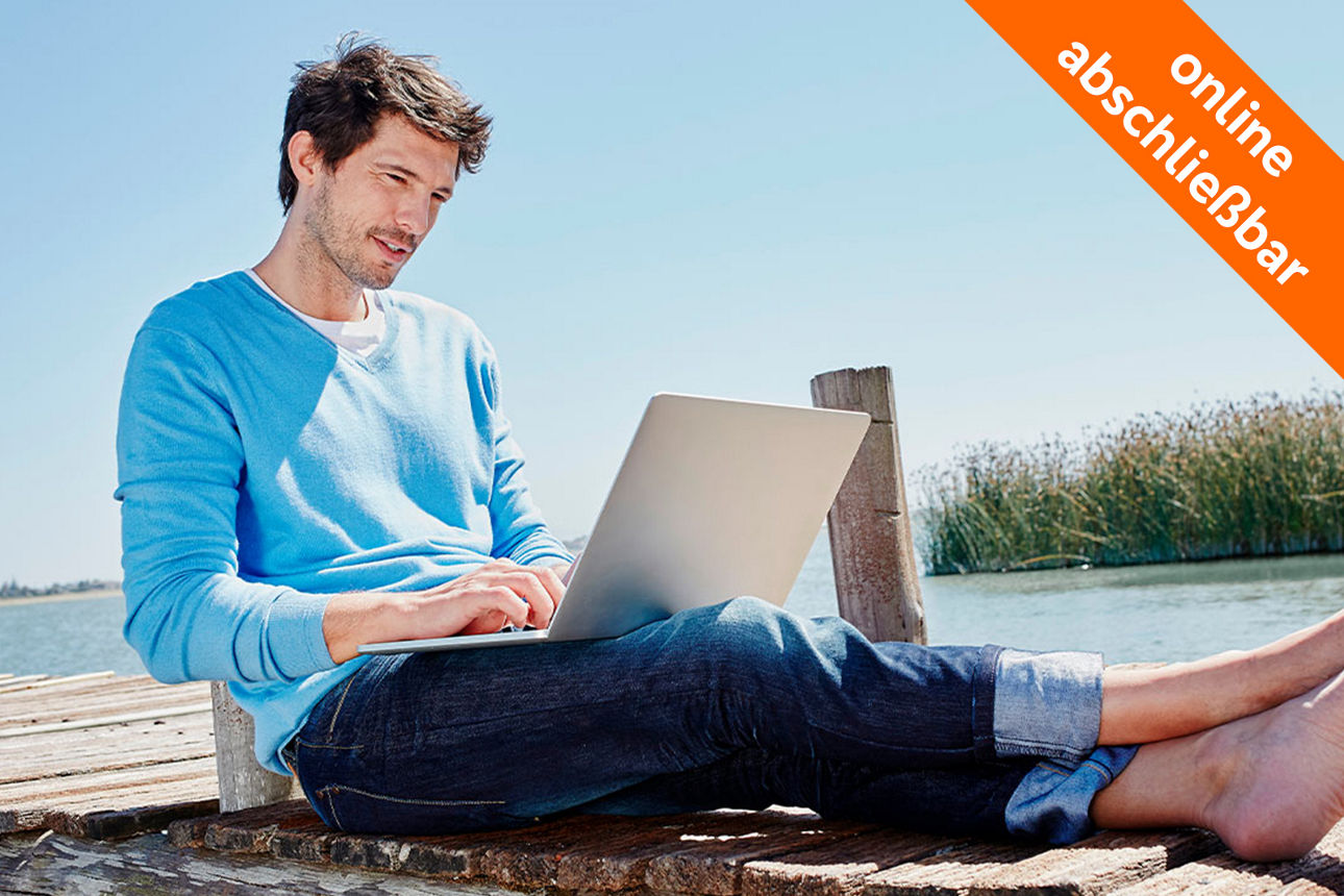 Mann sitzt mit Laptop am Steg