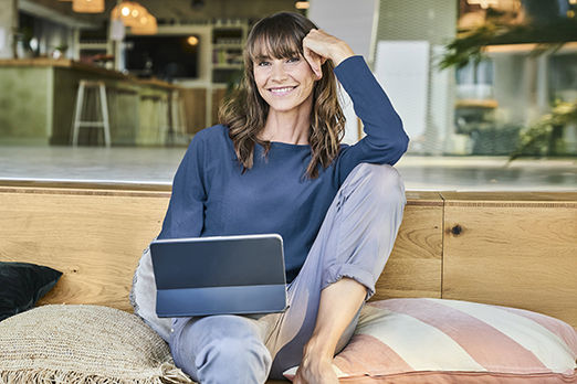 Eine Frau sitzt mit Tablet gemütlich auf einer Couch