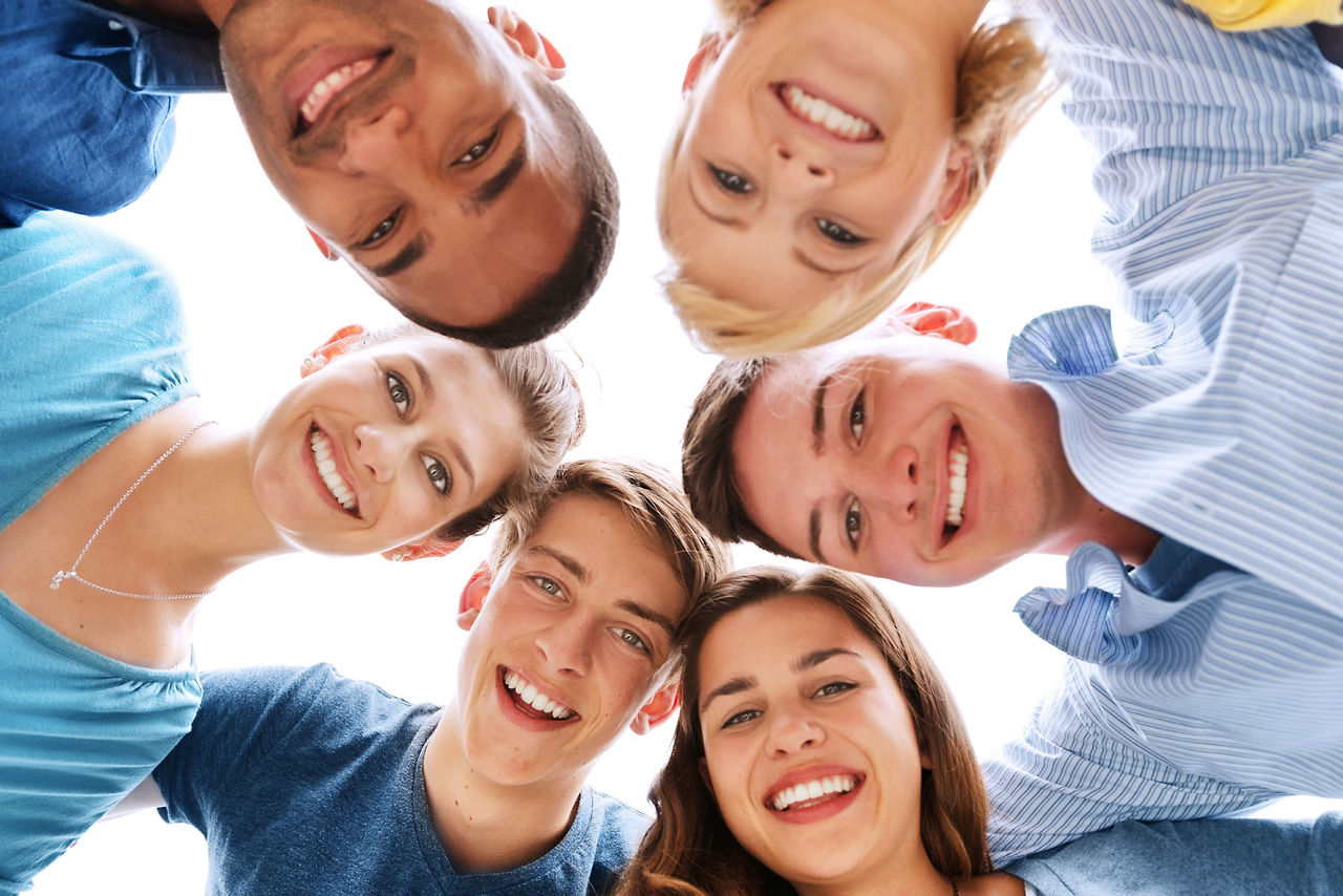 Gruppe von Jugendlichen stehen im Kreis und lächeln