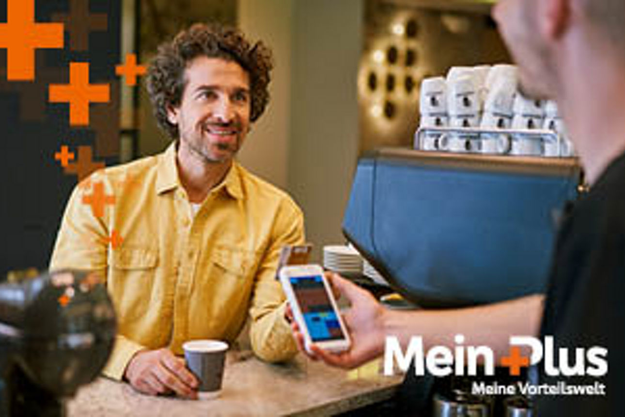 Person hält an einer Kaffeebar sein Smartphone zur Bezahlung einer weiteren Person hin