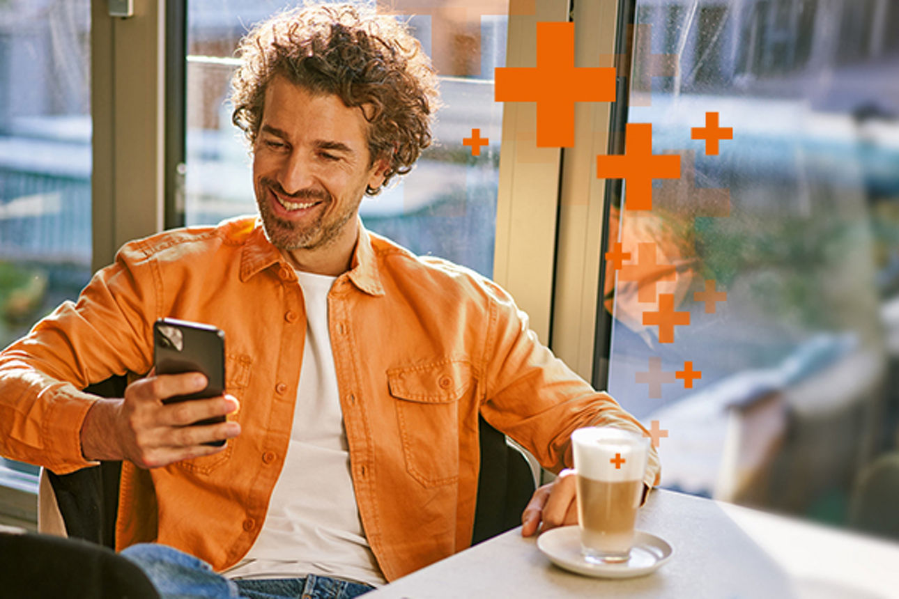 Mann mit Smartphone in der Hand in einem Cafe