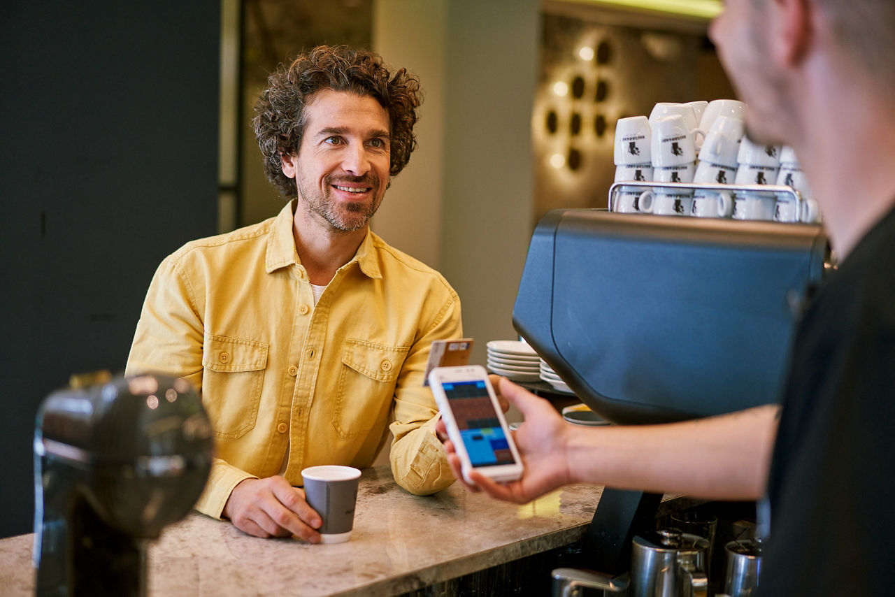 Mann zahlt in einem Café mit seiner girocard.