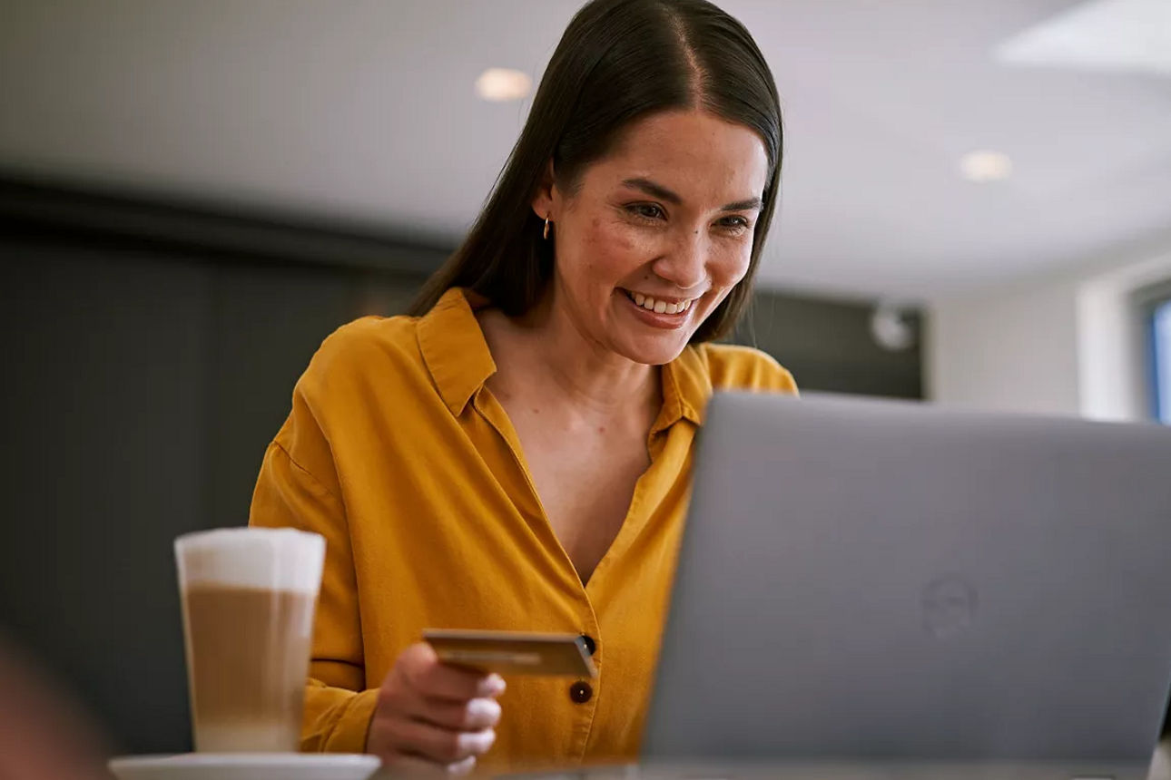 Frau sitzt mit girocard in der Hand am Laptop