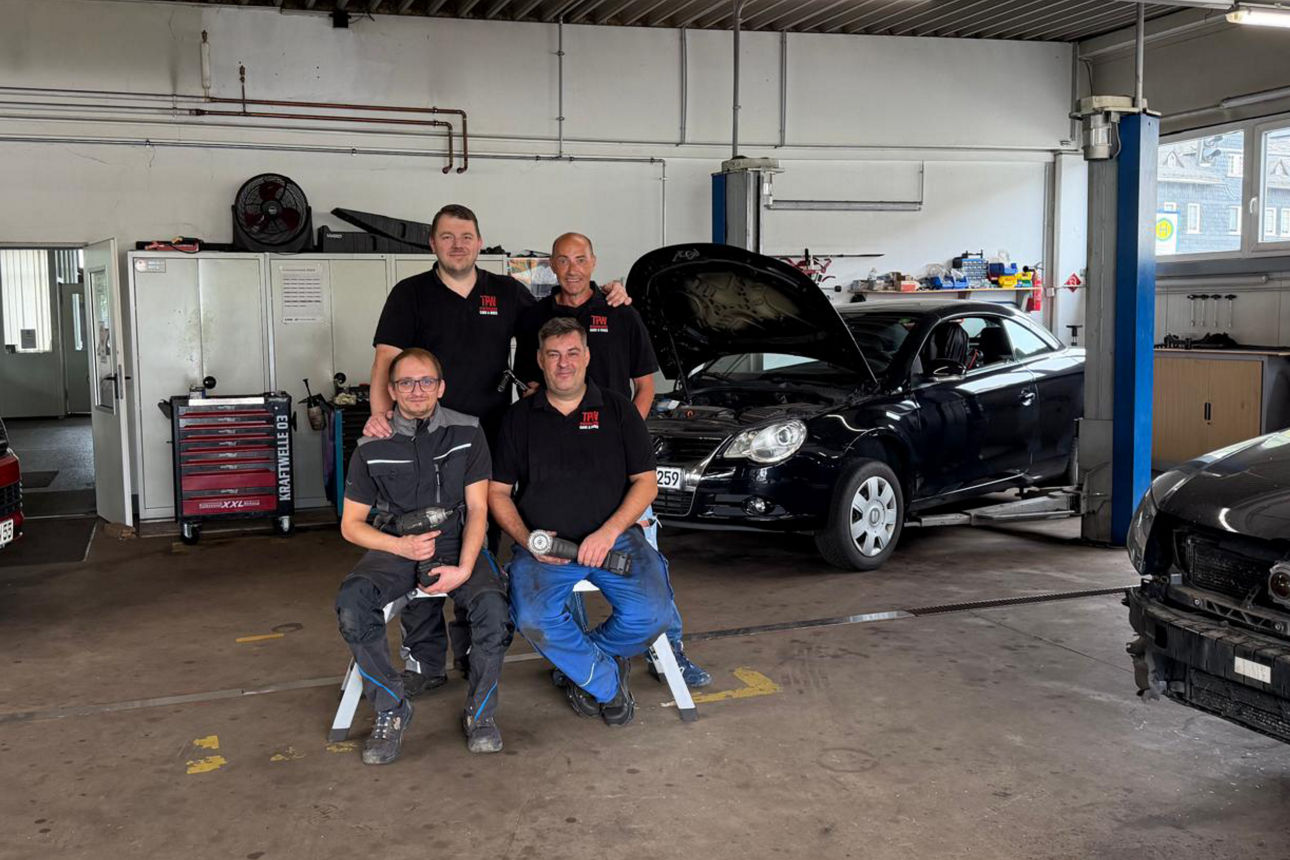 Vier Männer in einer Werkstatt mit Autos