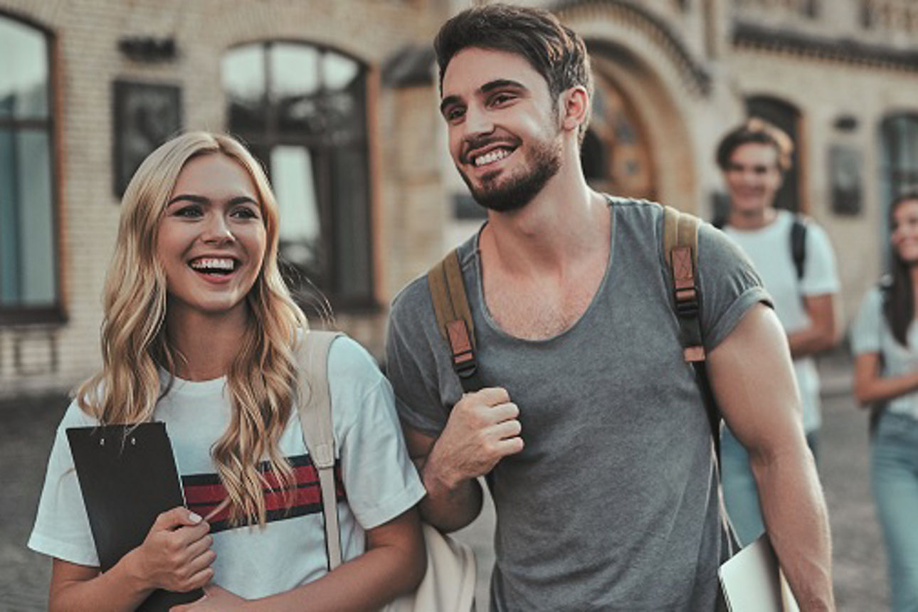 Junge Menschen gehen lachend nebeneinander