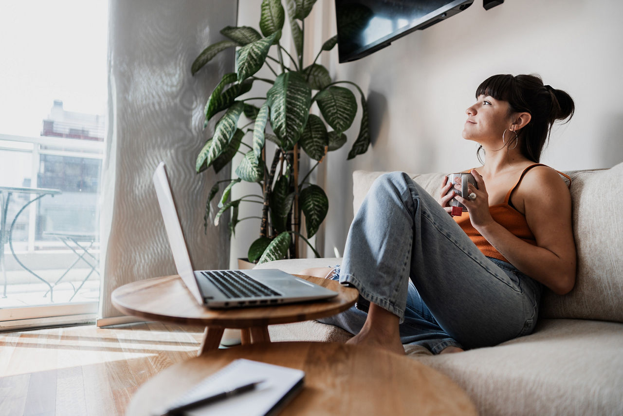 Frau sitzt entspannt mit einer Tasse Kaffee auf dem Sofa