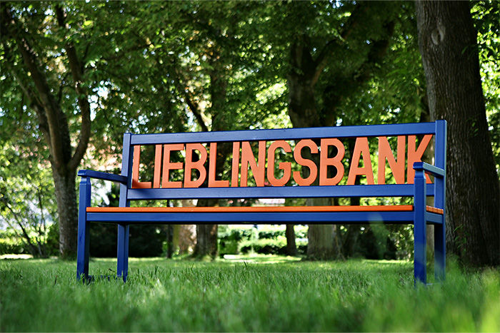 Eine aus Holzgeschnitzte Lieblingsbank stehend auf einer Wiese.