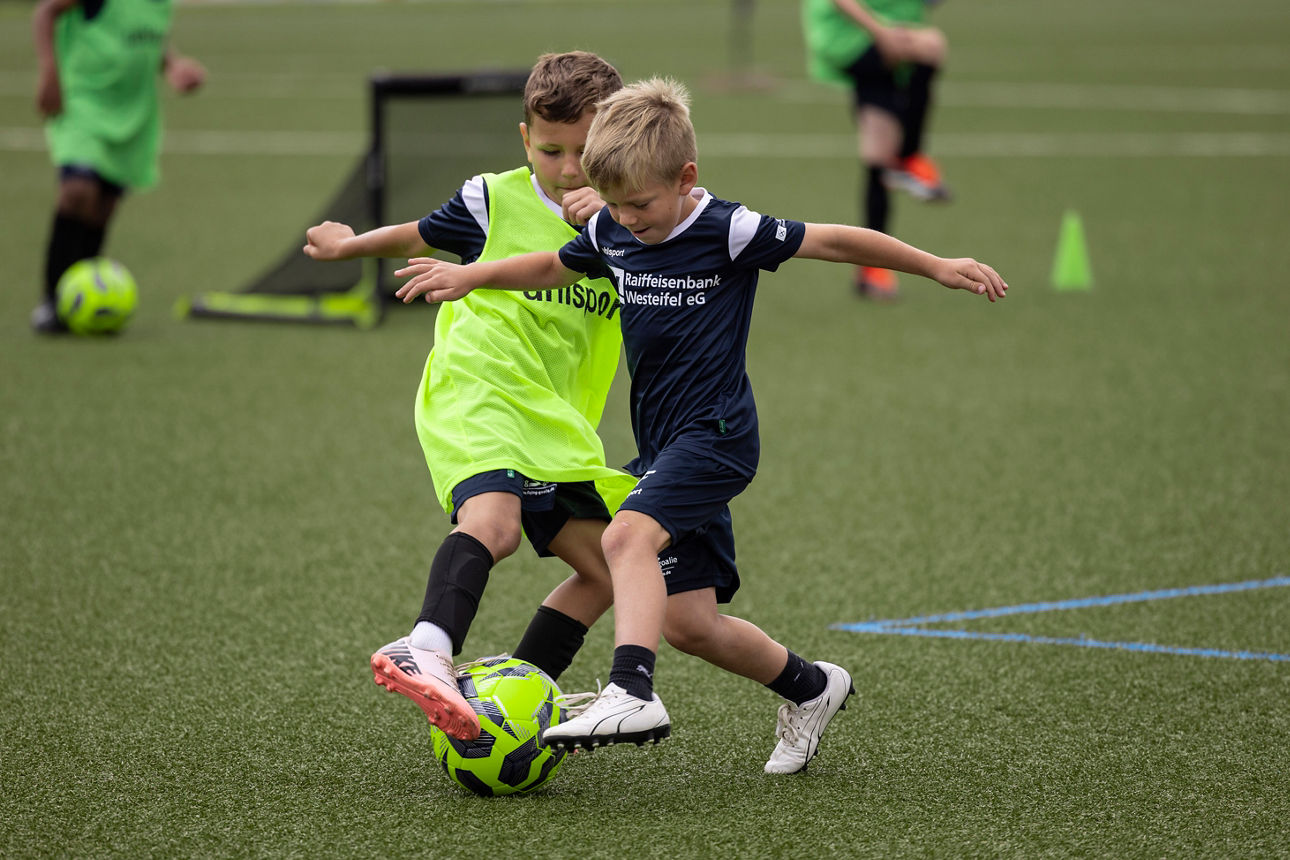 Eine Kinder-Fußballmannschaft in Raiffeisenbank Westeifel-Trikots beim Spiel