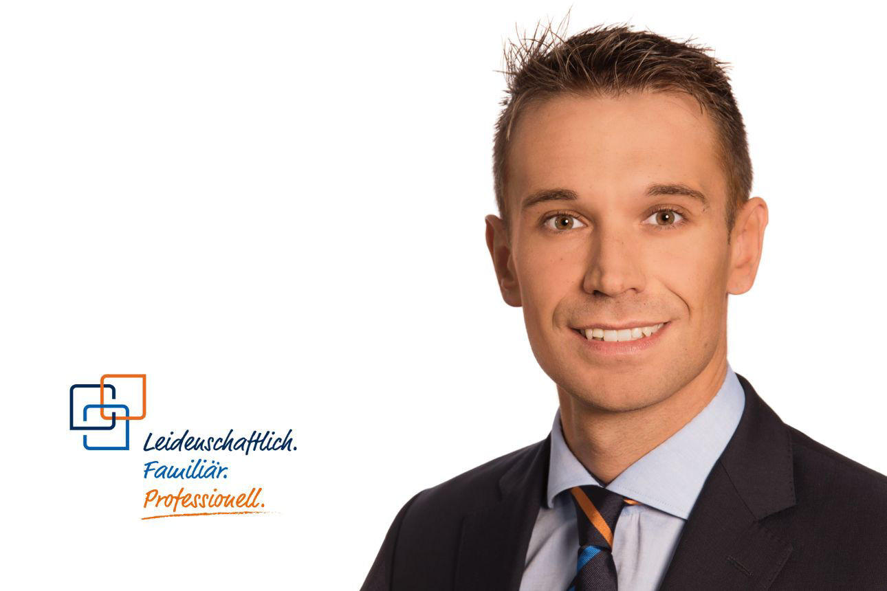 Porträt von Michael Grimeis, einem lächelnden jungen Mann mit kurzen, gestylten Haaren im dunklen Anzug mit orange-blau gestreifter Krawatte. Daneben das Firmenlogo und der Slogan "Leidenschaftlich. Familiär. Professionell."