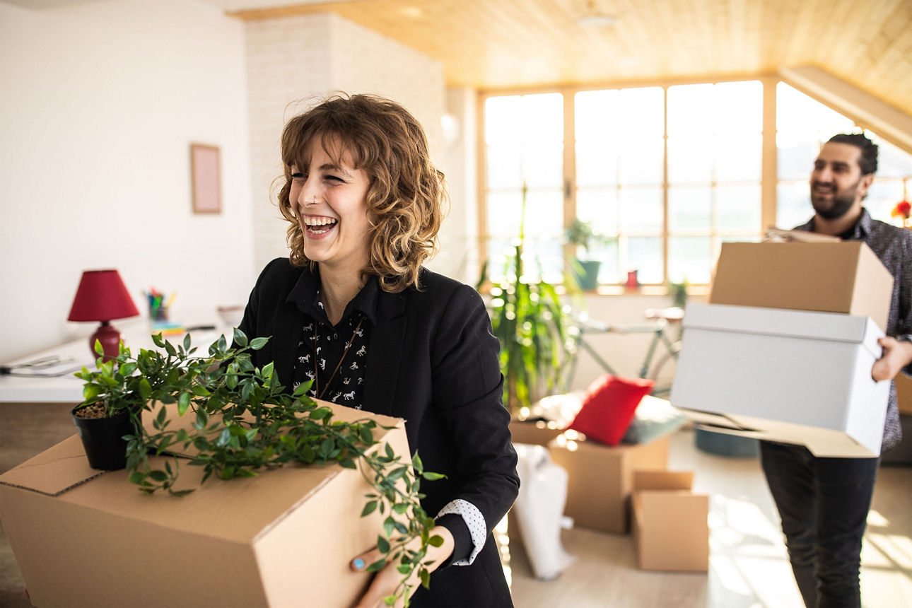 Zwei Personen freuen sich beim Einräumen einer neuen Mietwohnung