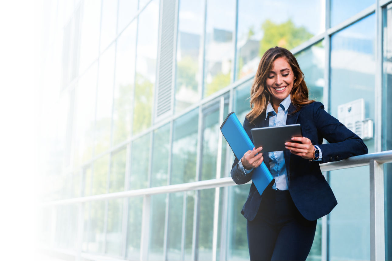Frau mit Tablet in der Hand vor Bürogebäude