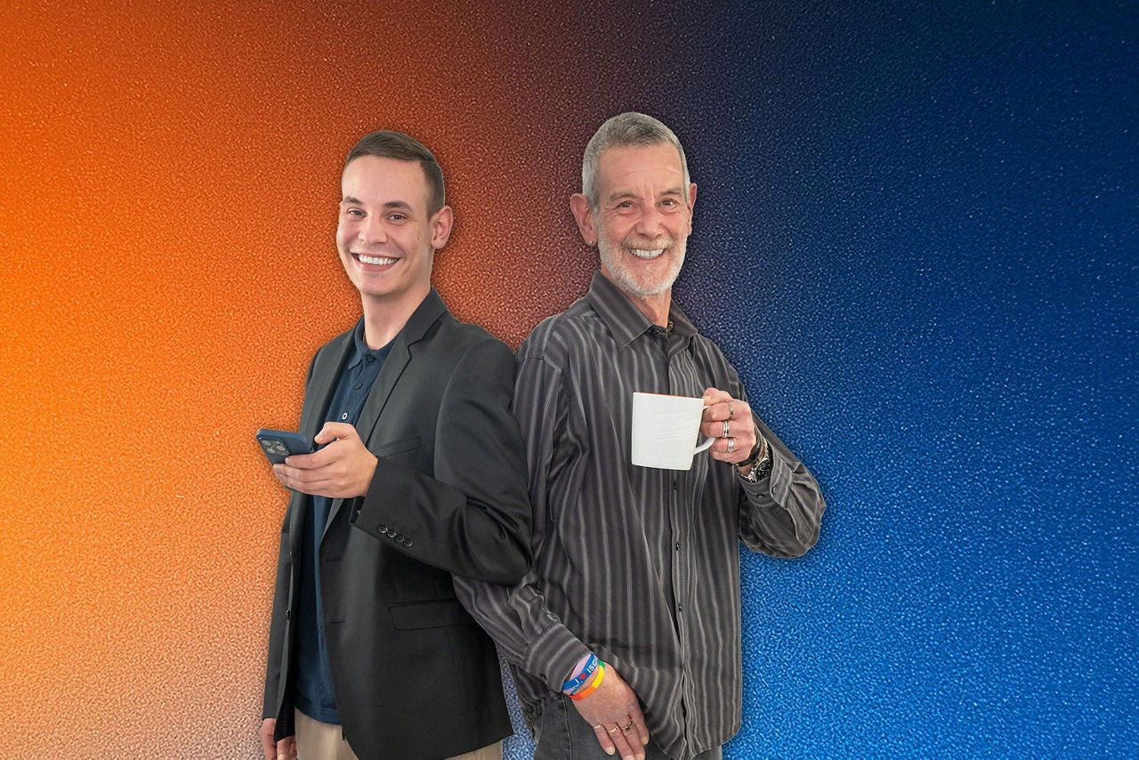 Zwei Elmshorner Kollegen stehen Rücken an Rücken, eine hält ein Smartphone , die andere eine Kaffeetasse