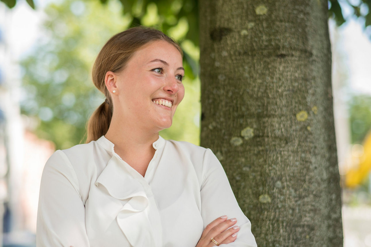 Frau steht vor einem Baum