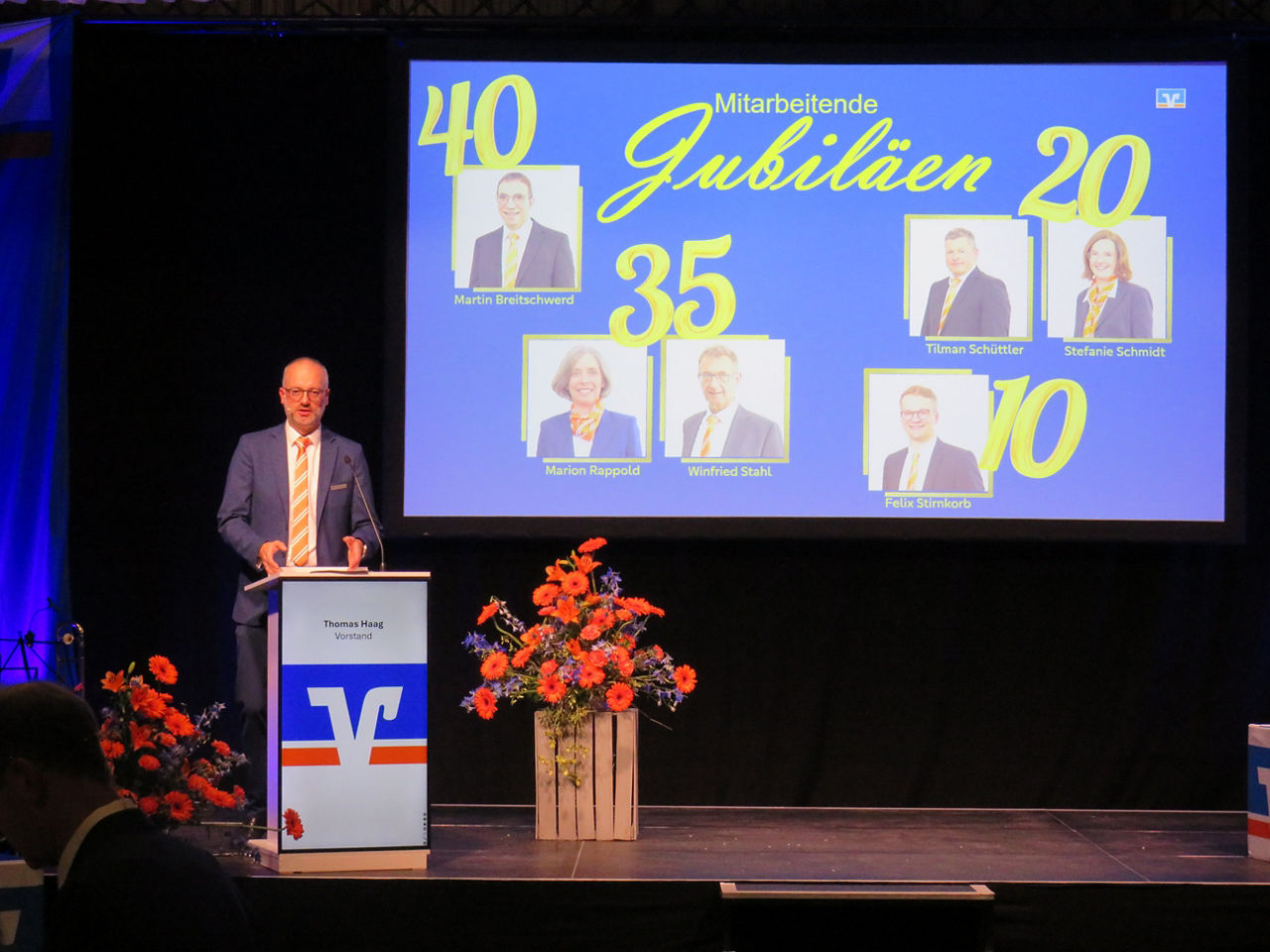 Vorstand Thomas Haag präsentiert in der Generalversammlung in einer PowerPoint lanjährige Mitarbeiterjubiläen
