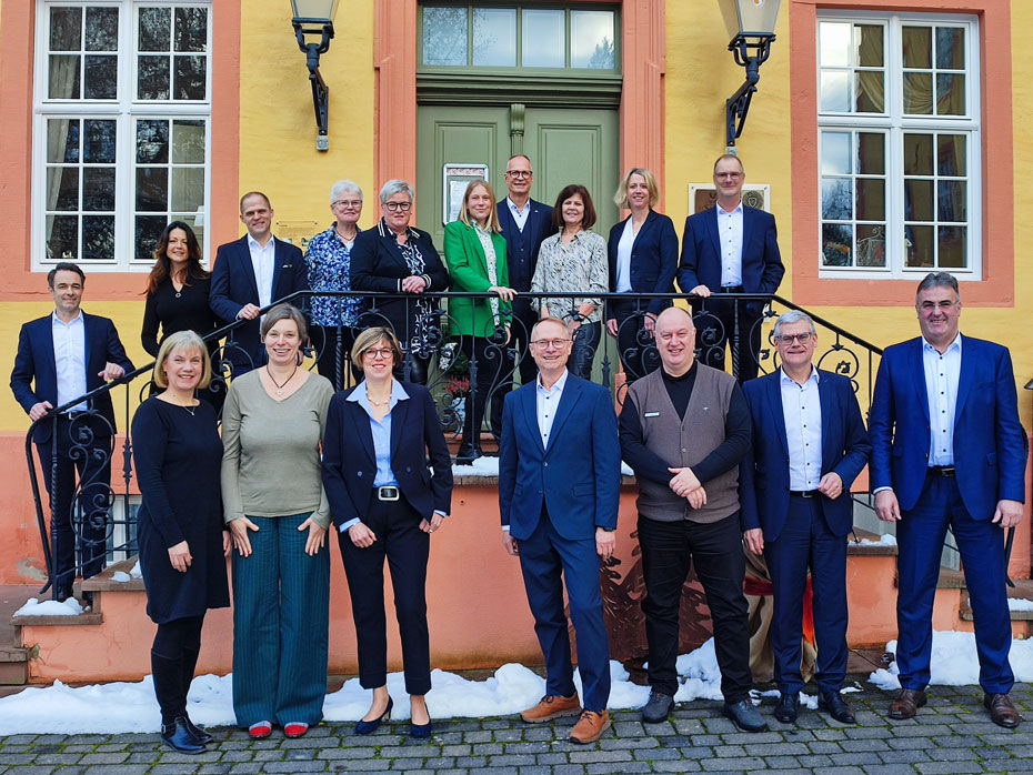 Das Bild zeigt die Ehrung langjähriger Mitarbeiter der VR Bank. Stolze Jubilare stehe und lächeln, umgeben von Kollegen und Vorgesetzten.