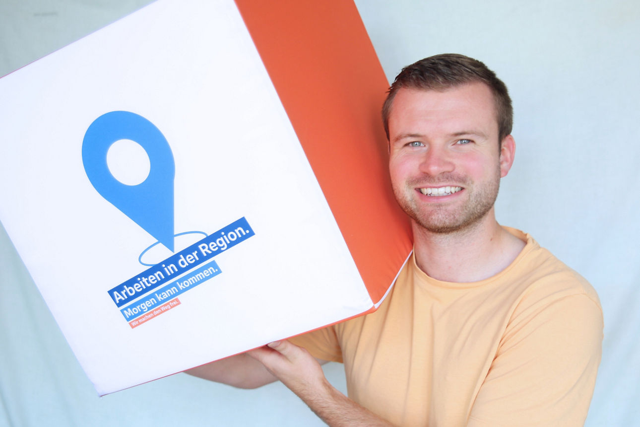 Mitarbeiter hält einen überdimensionalen Würfel in der Hand