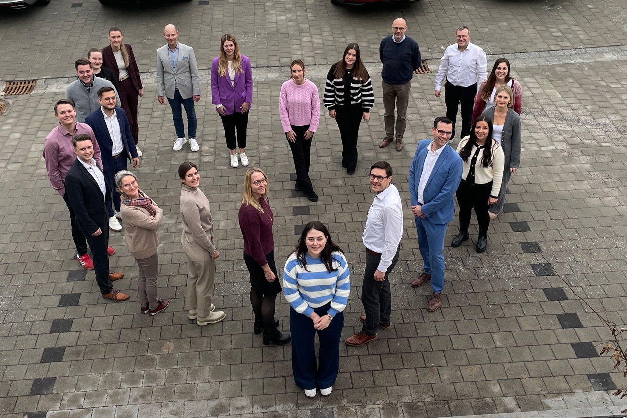 Mitarbeiter der Bank stehen herzförmig und schauen nach oben