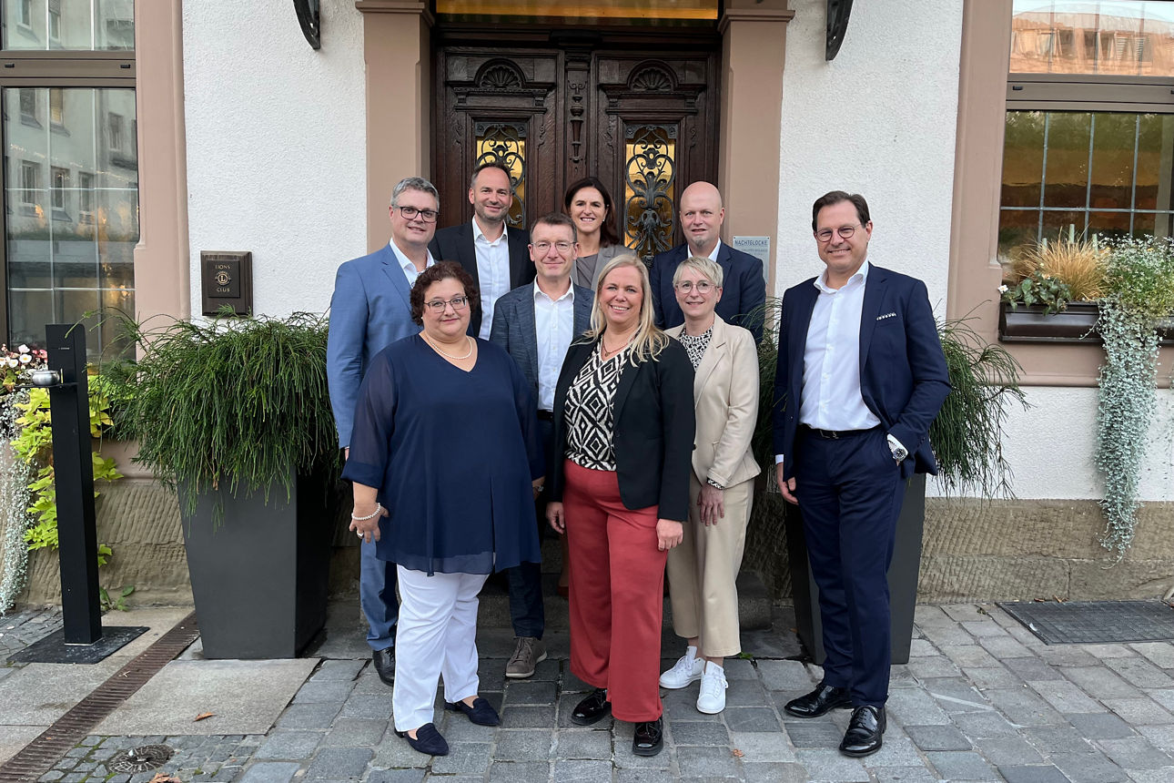 Auf dem Bild stehen fünf Männer und vier Frauen. Sie sind in drei Reihen hintereinander aufgestellt und lächeln in die Kamera.