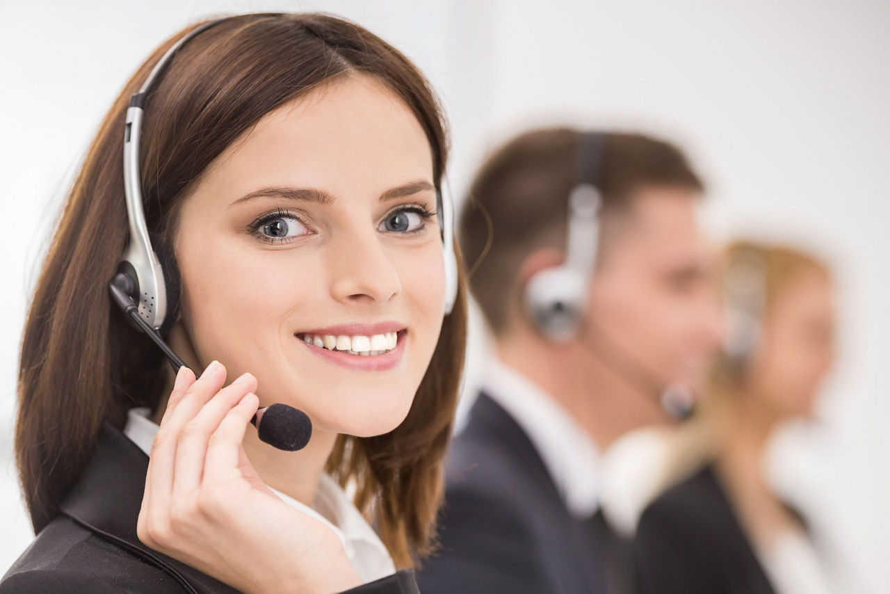 Eine Mitarbeitende des Mitglieder Dialog Center mit Headset lächelt ins Bild.