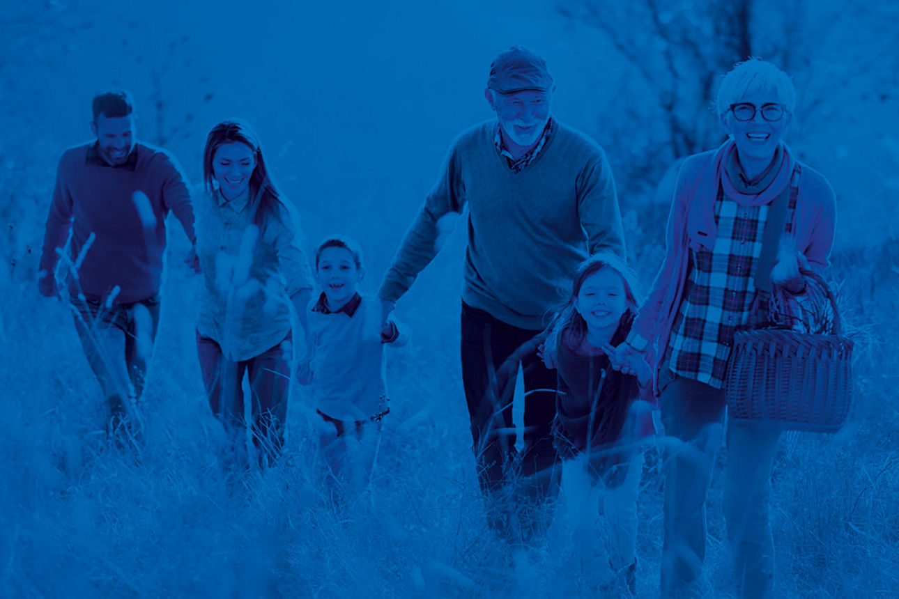 Eine fünfköpfige Familie geht über eine Wiese und hält sich an den Händen. 