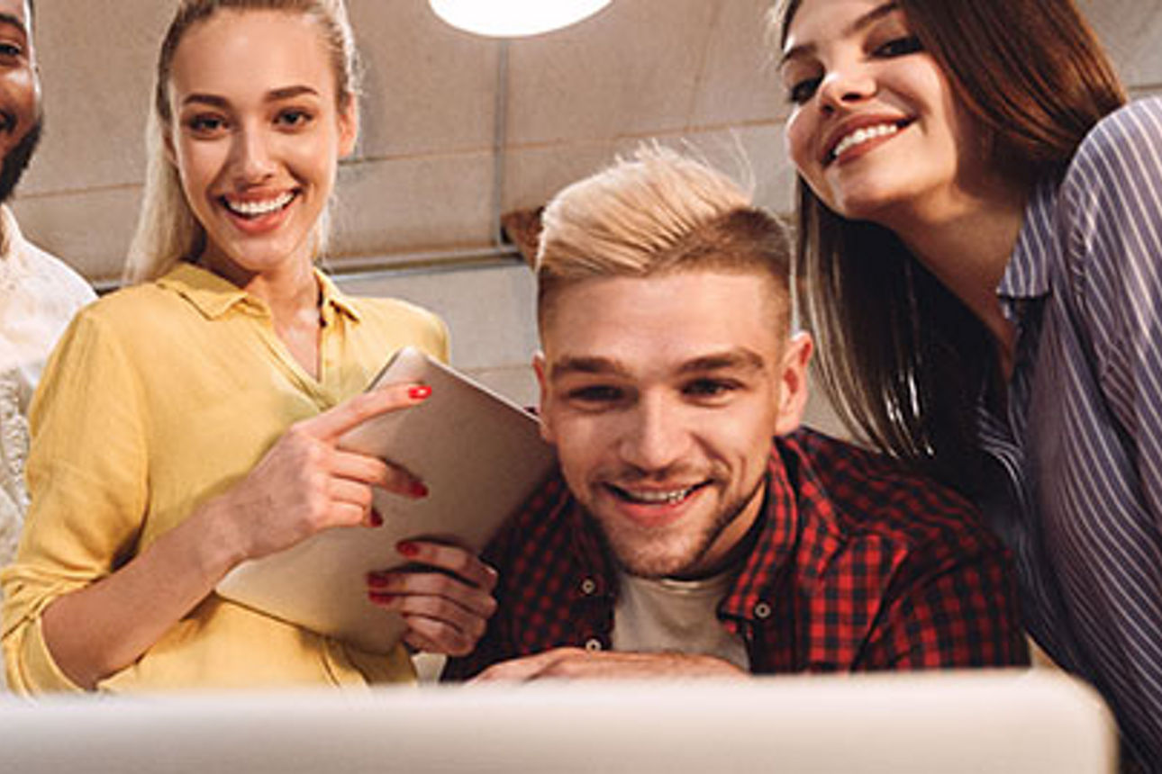 Drei junge Männer und drei junge Frauen schauen auf einen Laptop