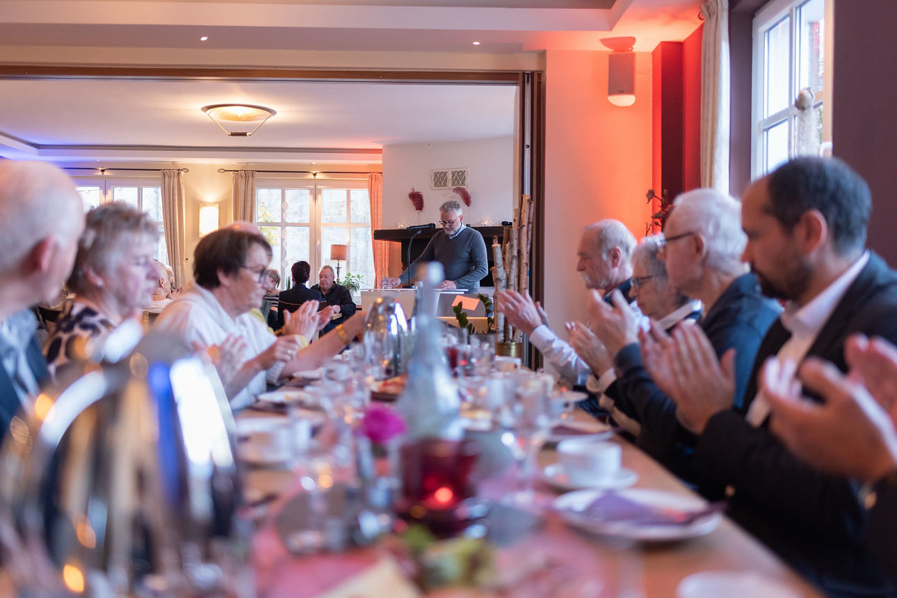 Volksbank Mitglieder und Mitarbeiter sitzen klatschend im Restaurant