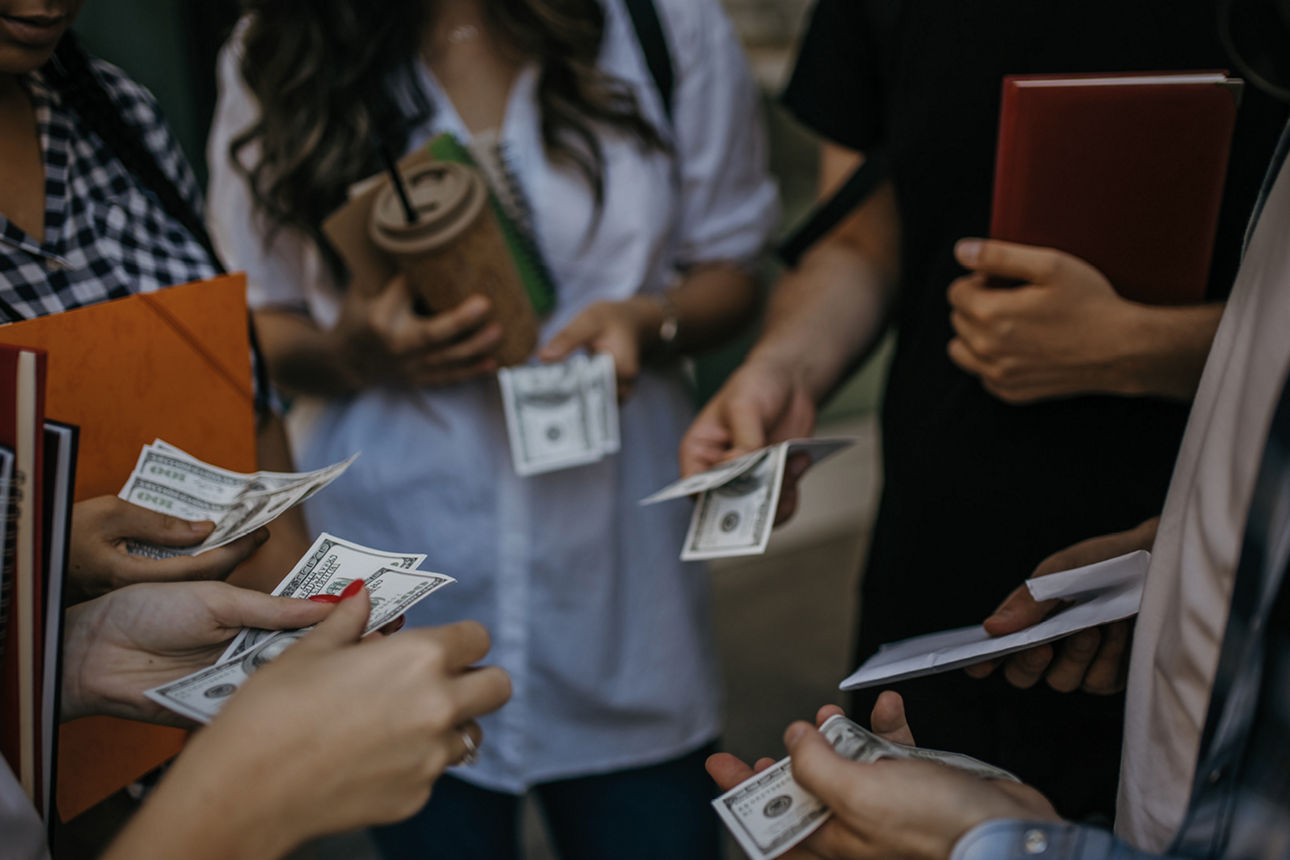 Verschiedene Personen die im Kreis Geldscheine in der Hand halten.