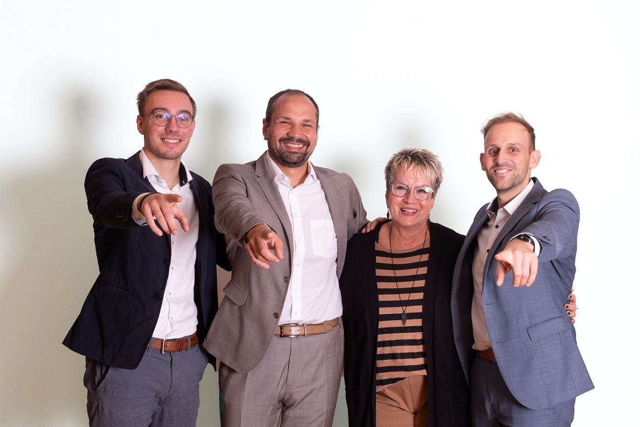 Vier Mitarbeitende der Volksbank Schermbeck stehen nebeneinander und zeigen in die Kamera.