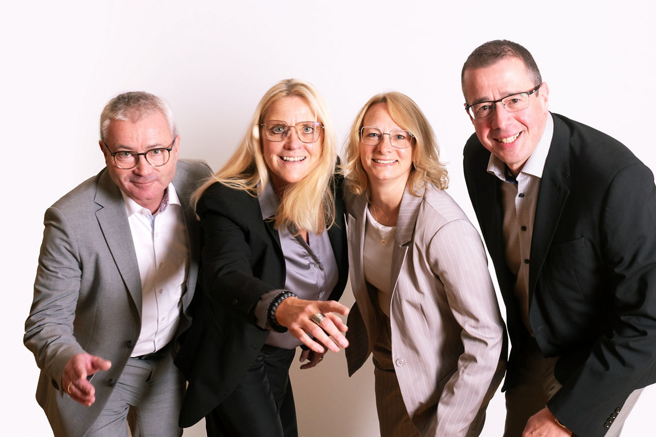    Zwei Frauen und zwei Männer stehen nebeneinander und schauen in die Kamera