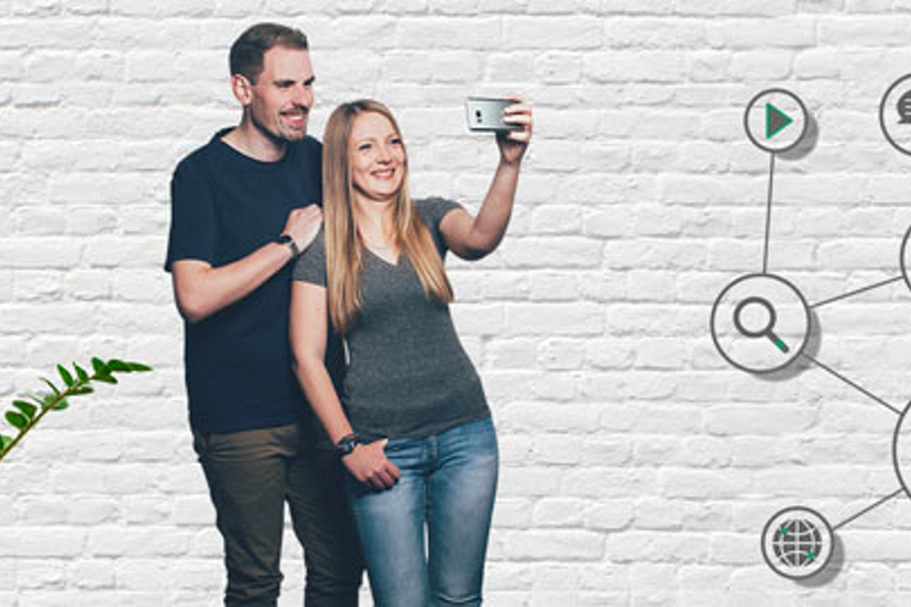 Mann und Frau stehen voreinander und machen ein gemeinsames Selfie