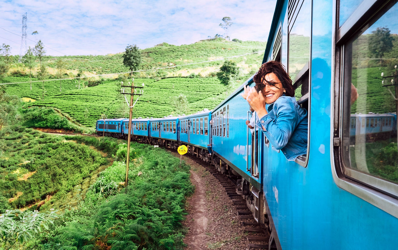 Frau schaut aus einem Fenster in einem historischen Zug in Sri Lanka