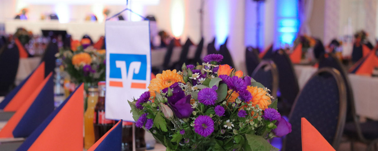 Detailbild eines Tisches mit Blumen und Volksbank-Wimpel