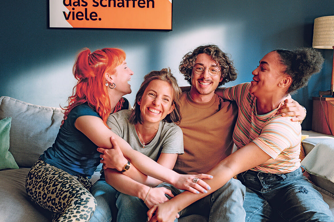 Vier lachende junge Menschen auf einem Sofa