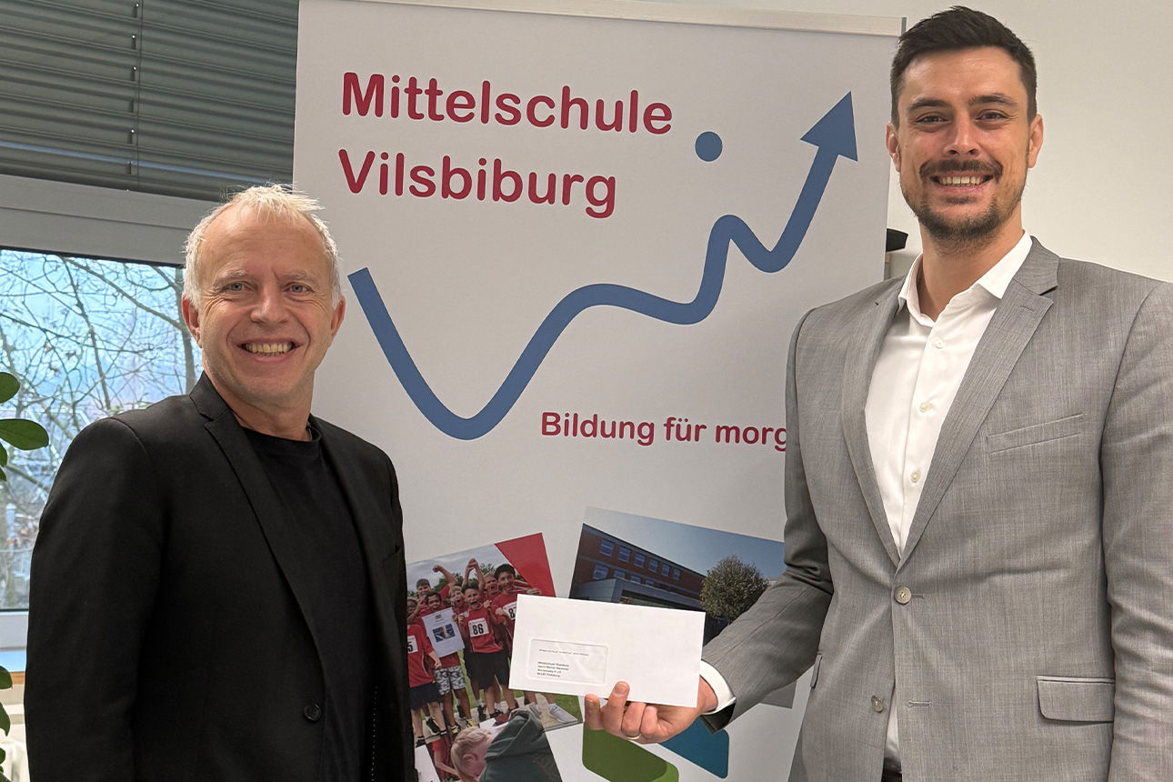 Zwei Männder lächeln in die Kamera. Sie halten einen Briefumschlag in der Hand.