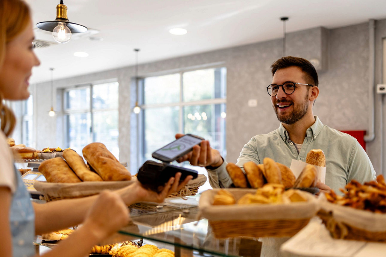 Mann bezahlt in Bäckerei mit dem Smartphone