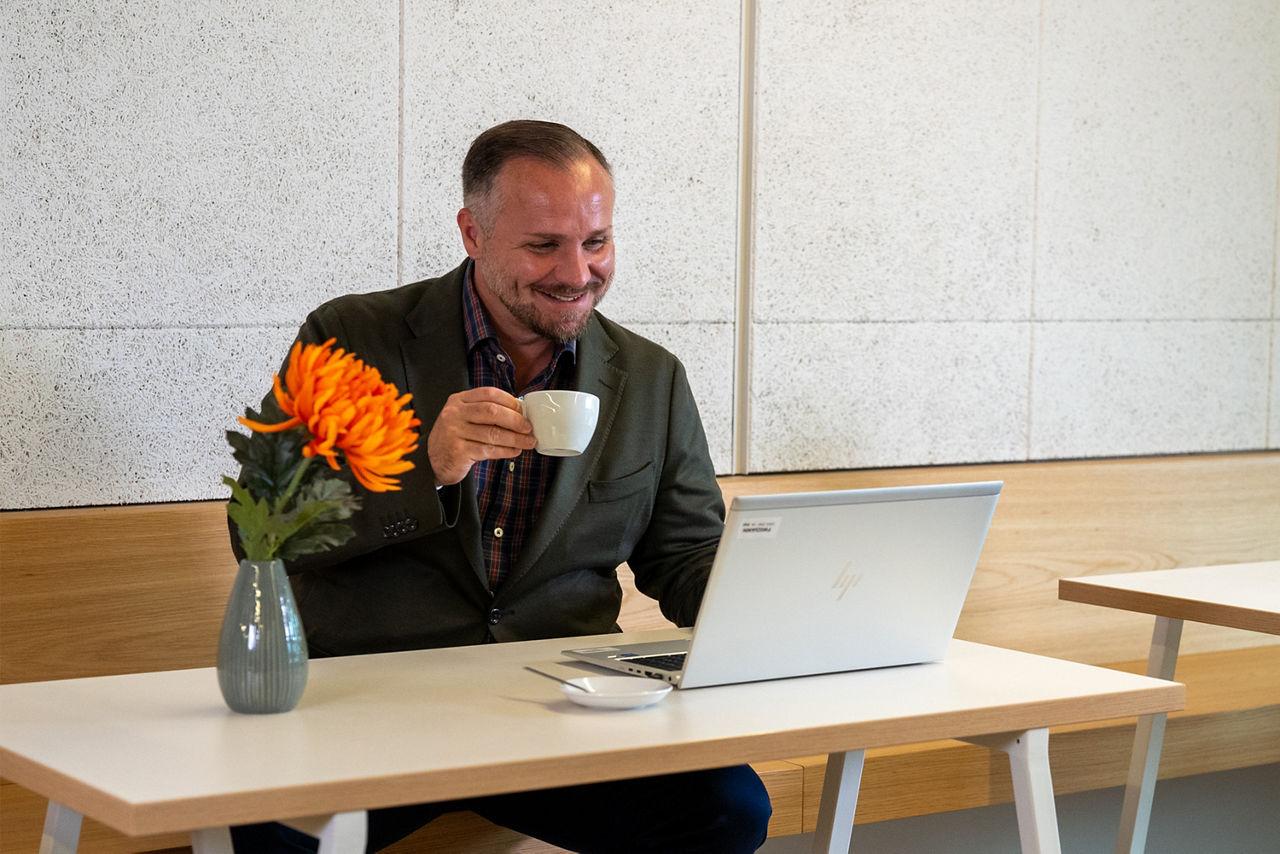 Mann sitzt mit einer Tasse in der Hand vor dem PC