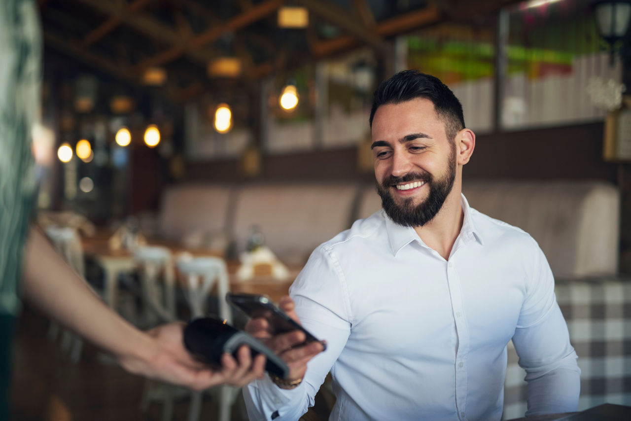 Mann bezahlt im Restaurant mit dem Smartphone