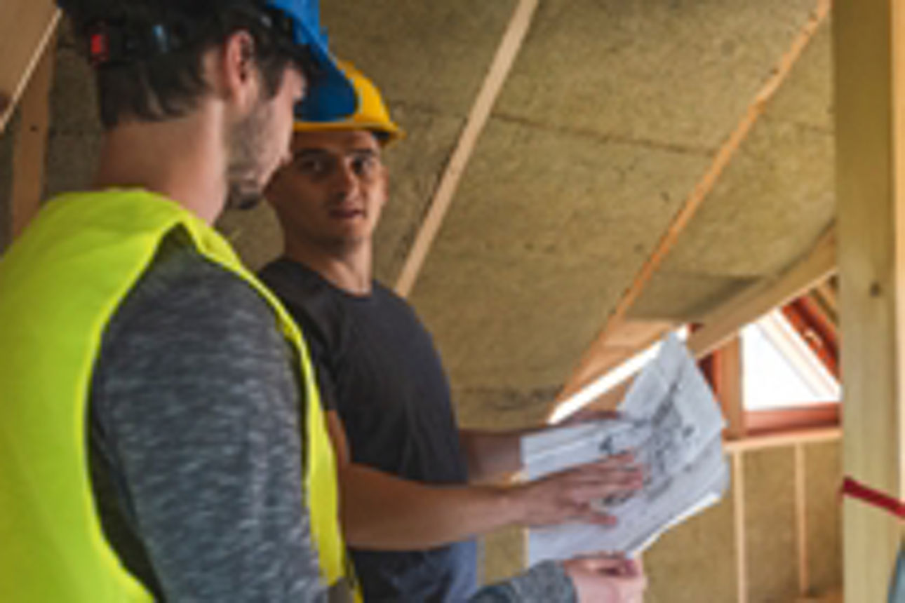 Zwei Männer auf einer Baustelle lesen einen Plan