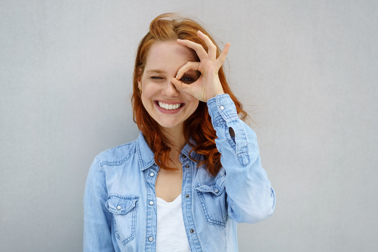 lachende frau schaut durch ihre finger