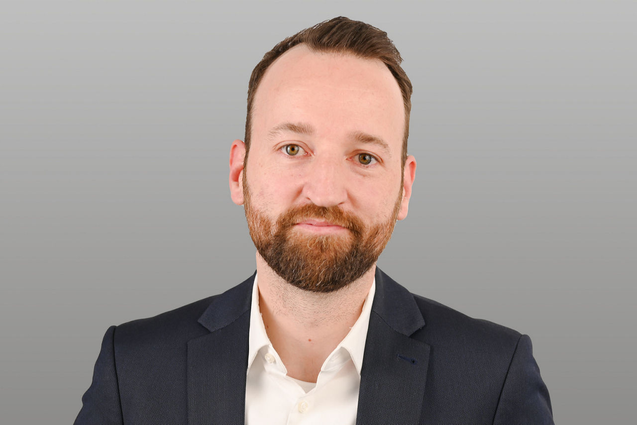 Privatkundenberater Christian Moog vor grauen Hintergrund