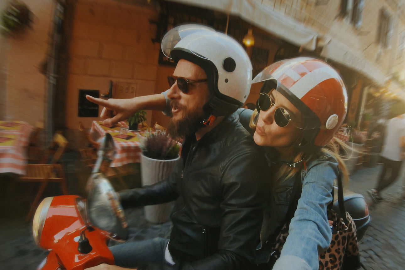 Zwei Freunde fahren gemeinsam auf einem Roller durch Rom.
