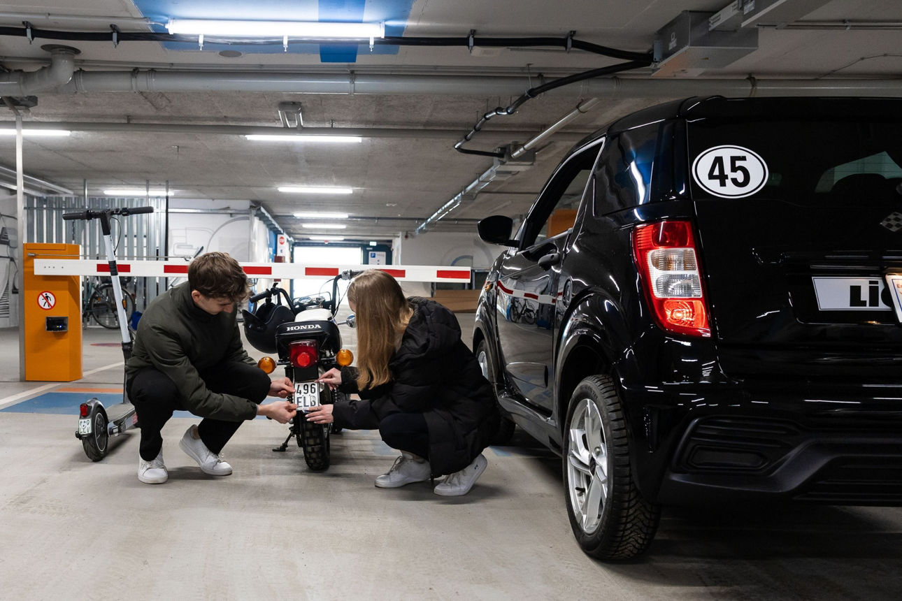 Zwei Jugendliche montieren ein Versicherungskennzeichen auf ein Moped