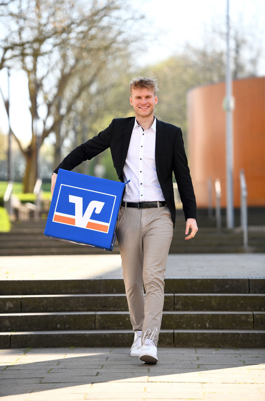 Auszubildender läuft mit Volksbank-Würfel Treppen runter