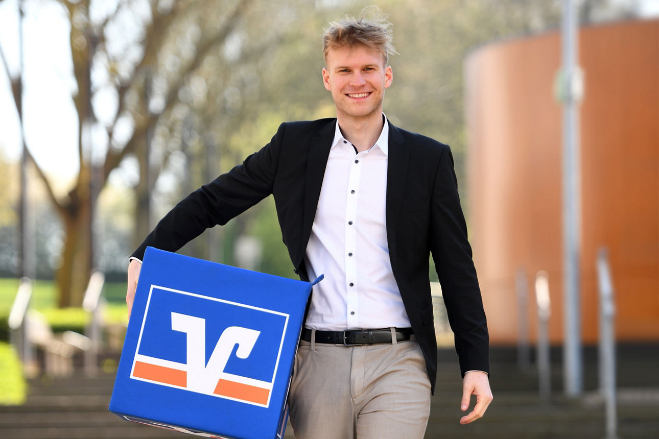 Auszubildender läuft mit Volksbank-Würfel Treppen runter
