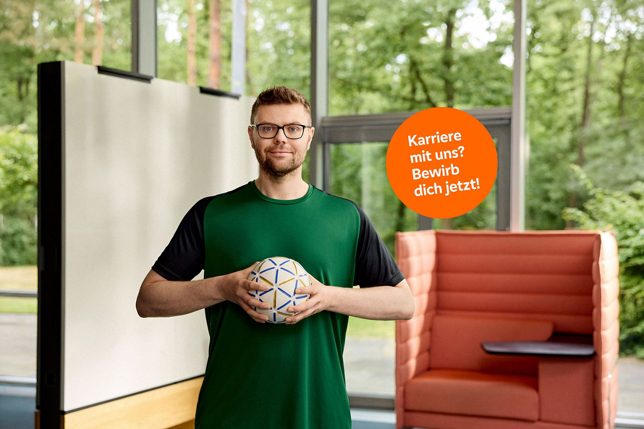 Ein junger Mann hält einen Fußball in der Hand.