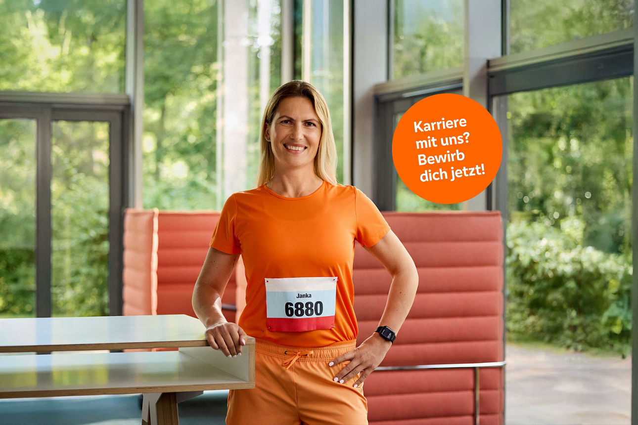 Läuferin, hat eine Startnummer auf ihrem Sportshirt aufgeklept und lächelt in die Kamera.